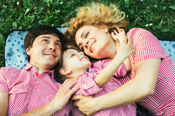 Fototapeta premium Unique perspective of happy european family smiling while lying down on the green grass in the park