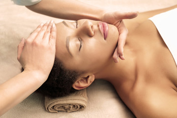 Beautiful African-American girl having massage in spa salon