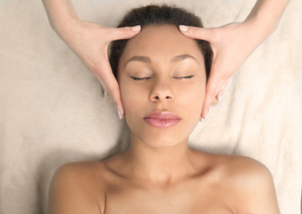 Fototapeta na wymiar Beautiful African-American girl having massage in spa salon