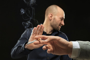 Young man refusing from smoking on black background