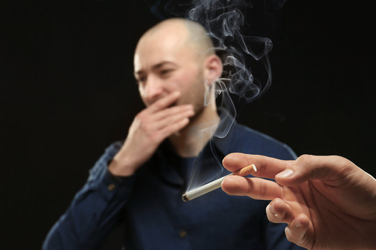 Young man refusing from smoking on black background