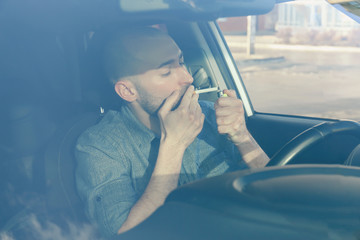 Handsome man smoking cigarette in car