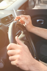 Male hands with cigarette on steering wheel