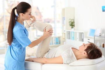 Female orthopedist massaging middle-aged woman in clinic