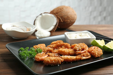 Plate with delicious coconut shrimps on table