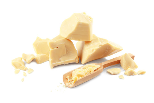 Wooden scoop and pieces of cocoa butter on white background