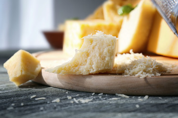 Wooden board with grated cheese on table