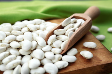 Scoop with butter beans on wooden cutting board