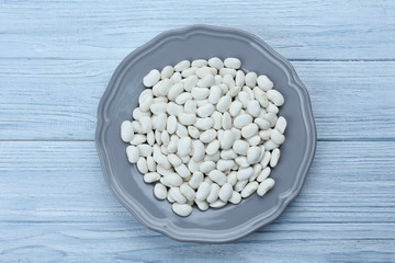 Plate with butter beans on wooden table, top view