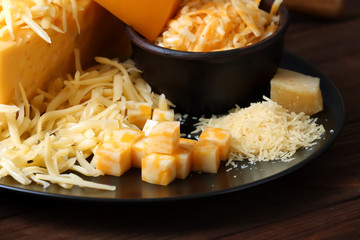 Plate and bowl with grated cheese on wooden table