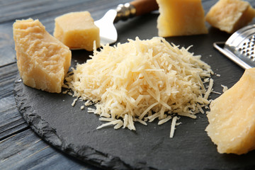 Slate plate with cheese and grater on wooden background