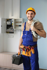 Young smiling electrician with bunch of wires indoors