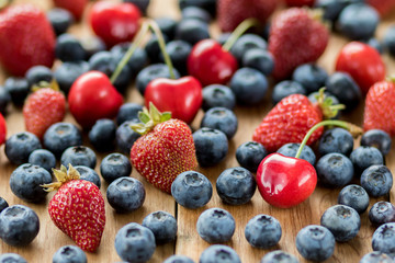 Strawberries, cherries and blueberry on wooden table, background