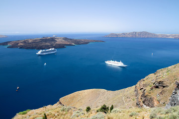 Fototapeta na wymiar Zwei Kreuzfahrtschiffe ankern im blauen Meer im Krater des erloschen Vulkans von Santorin.