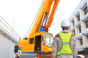 Fototapeta na wymiar Back view of Male construction worker against crane background.