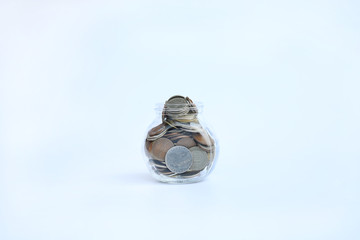 International coins in a glass jar on white background.