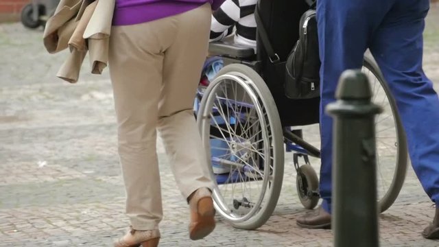 Family walking with woman in wheelchair, slow motion