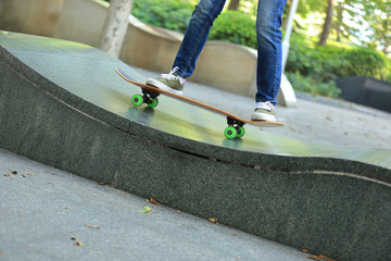 young skateboarder legs practicing at skatepark