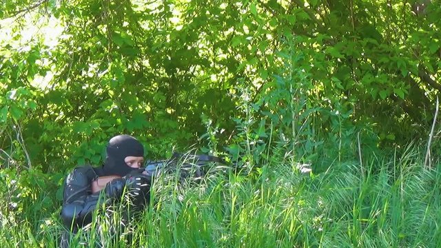 The Russian special forces soldier in armor and balaclava aiming from the crossbow and giving the order to move forward. Marine recon.