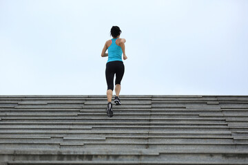 Obraz na płótnie Canvas Sporty female running up on stone stairs