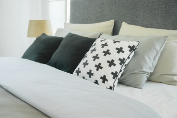Modern bedroom interior with pillows and reading lamp, black and white color scheme