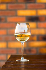 Glass with white wine on the desk, brick background