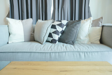 Stylish pillows on gray sofa with wooden table in the living room