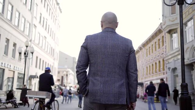 Business man in suit goes back to the camera on a busy city street