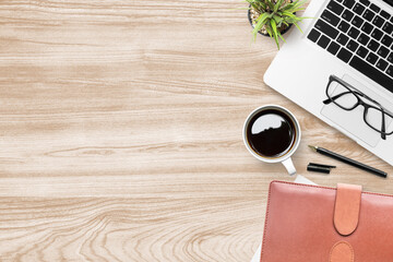 Wood office desk table with laptop, cup of coffee and supplies. Top view with copy space, flat lay.