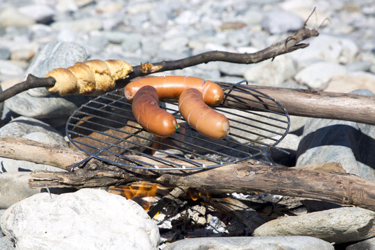 Knacker sausages and twist bread on open fireplace