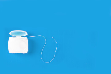 Dental floss in container on blue background - obrazy, fototapety, plakaty