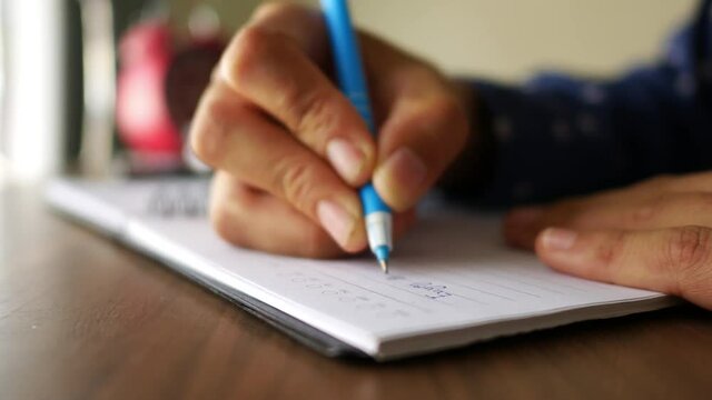 Female hands with pen writing on notebook.
