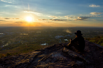 Man traveler is using digital phone on cliff with beautiful landscape sunset