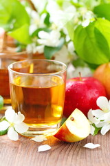 Sweet apple juice, apples and flowers on the table