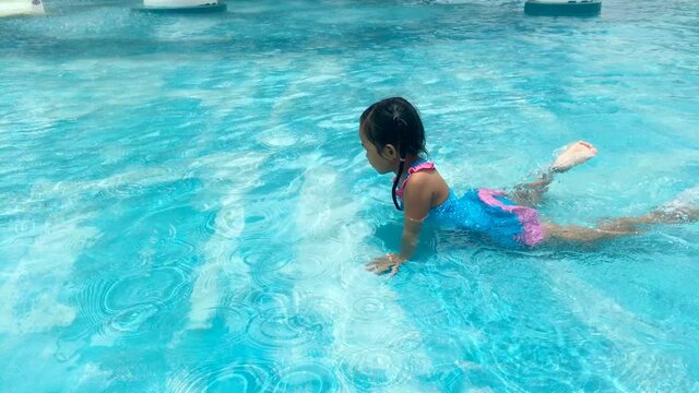 Asian little girl having fun in swimming pool, UHD 4k 3840x2160. 
