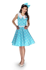 Beautiful woman in blue dress with polka dots with bow on head smiling looking at camera standing on white background