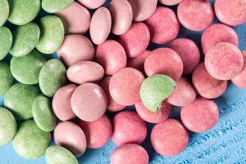 Red and green round chocolate candies on the blue wooden table