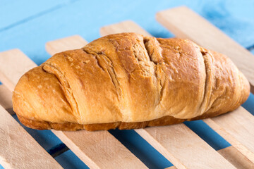 Chocolate croissant on the wooden planks background