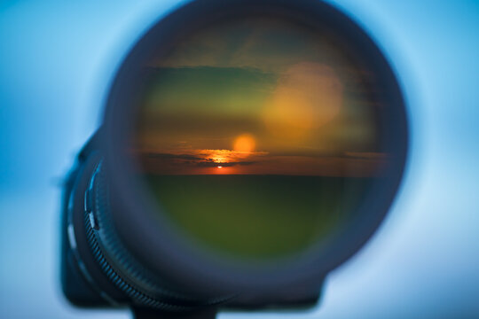 The camera lens with a landscape reflection on the background of the sky