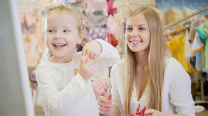 Mother and daughter having fun in front of the mirror