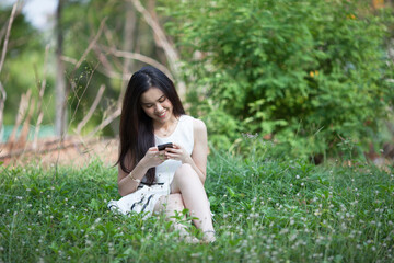 Naklejka na ściany i meble Thai pretty woman using mobile at the park