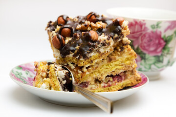 Piece of cake with hazelnuts, teaspoon and cup