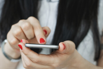 Girl with black hair in a white t-shirt holding smartphone and touching screen