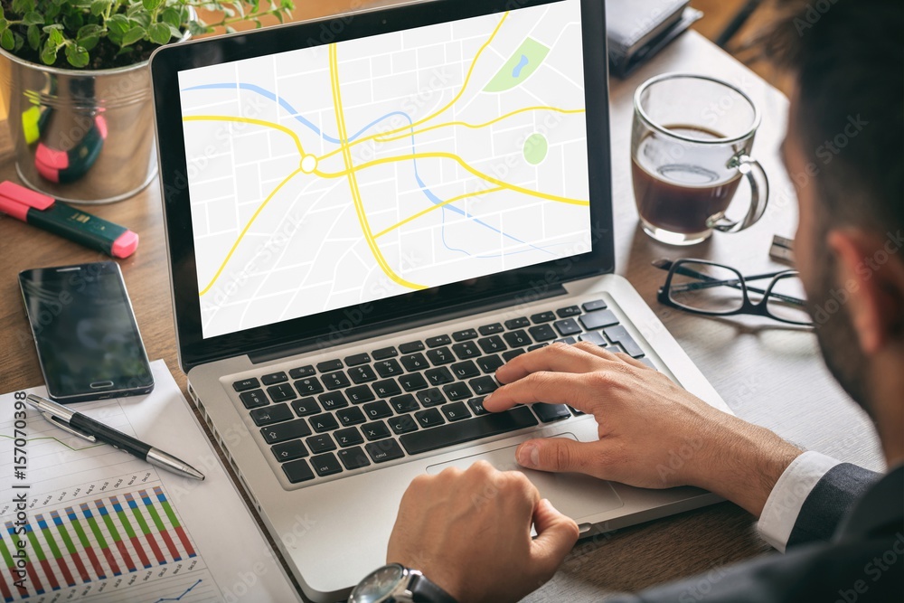 Wall mural man at work with a laptop - map on the computer screen