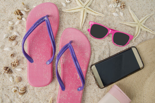 Smartphone and beach item on sand