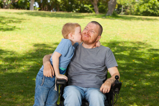 Little son kissing his disabled father.