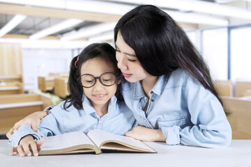 Teacher reading a book with her student