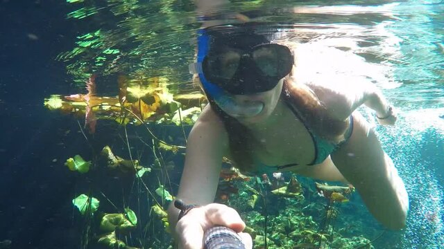 Beautiful young girl snorkeling in a turquoise water hole. Tulum, Mexico.