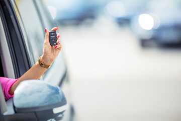 Attractive woman hand out window car holding car key.