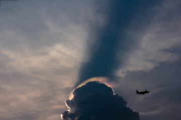 Cloud iridescence or rainbow cloud with an airplane